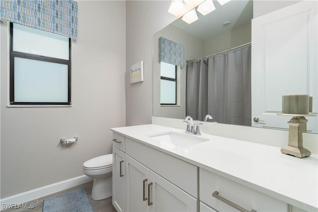 bathroom with vanity, toilet, baseboards, and a skylight