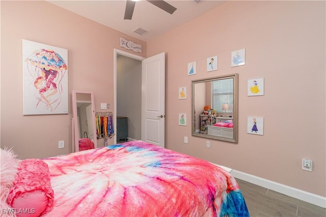bedroom featuring baseboards, visible vents, a ceiling fan, and wood finished floors