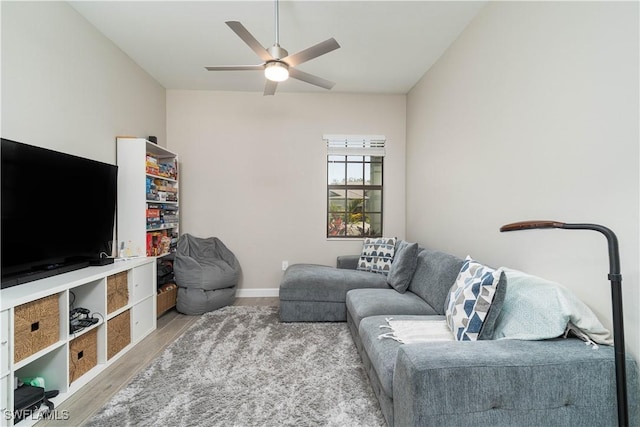 living area featuring a ceiling fan, baseboards, and wood finished floors