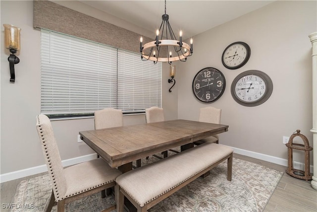 dining room with a notable chandelier, baseboards, and wood finished floors