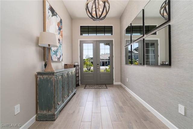 foyer featuring baseboards, french doors, a notable chandelier, and wood finished floors