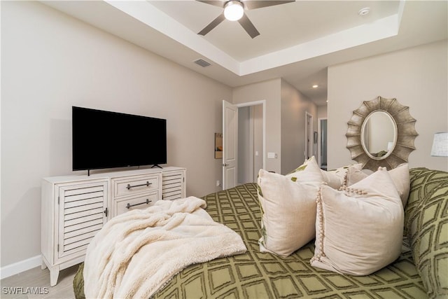 bedroom featuring light wood-style flooring, recessed lighting, ceiling fan, visible vents, and a raised ceiling