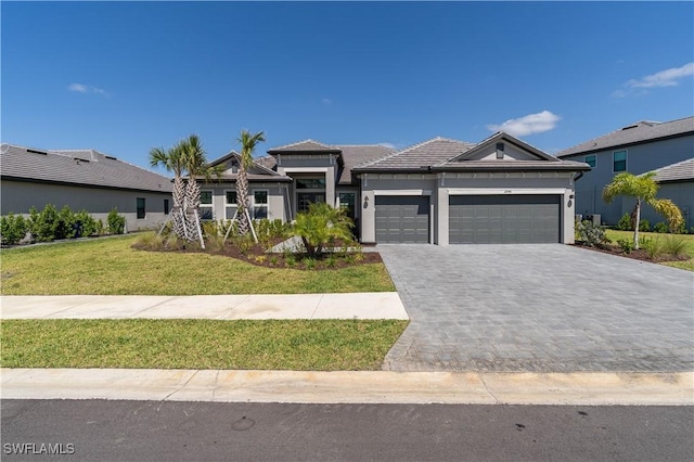 prairie-style house with a front lawn, stucco siding, a garage, and decorative driveway