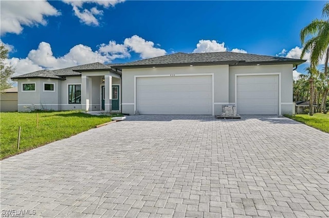 prairie-style home featuring a garage, stucco siding, decorative driveway, and a front yard