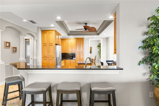 11239 Bienvenida Ct Unit 11C, Fort Myers, FL 33908 - kitchen with ornate columns, stainless steel refrigerator with ice dispenser, a breakfast bar, a ceiling fan, and decorative backsplash