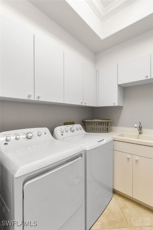 11239 Bienvenida Ct Unit 11C, Fort Myers, FL 33908 - clothes washing area featuring cabinet space, washing machine and dryer, light tile patterned flooring, and crown molding