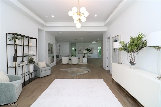 interior space featuring a tray ceiling, recessed lighting, wood finished floors, and a notable chandelier