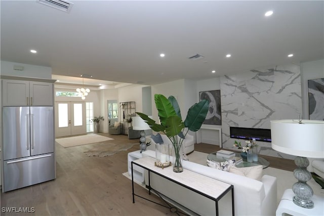 living area featuring light wood-type flooring, visible vents, a raised ceiling, and recessed lighting