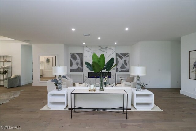 living room with wood finished floors, visible vents, baseboards, and recessed lighting