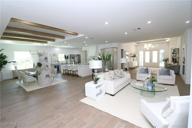 living area featuring beam ceiling, visible vents, recessed lighting, light wood finished floors, and a notable chandelier