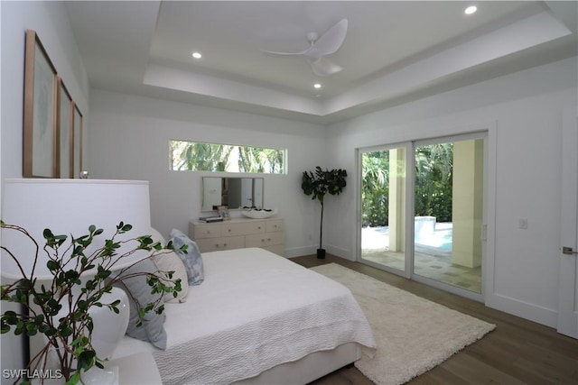 bedroom with wood finished floors, baseboards, a raised ceiling, access to outside, and recessed lighting