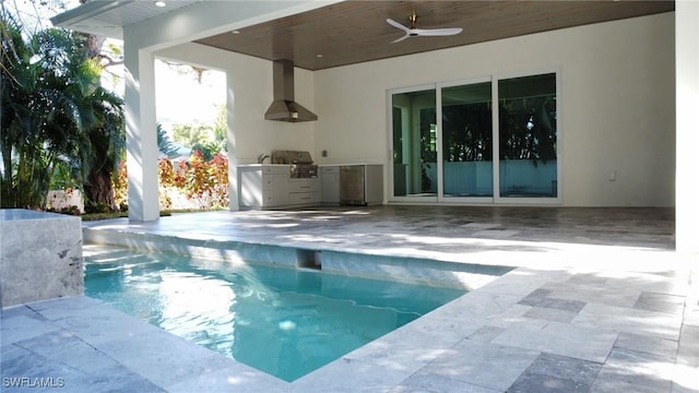 outdoor pool with a patio area, a grill, an outdoor kitchen, and ceiling fan
