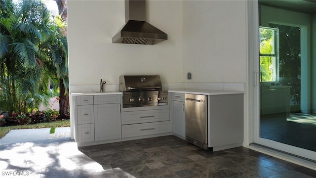 kitchen featuring wall chimney range hood, light countertops, fridge, and a sink