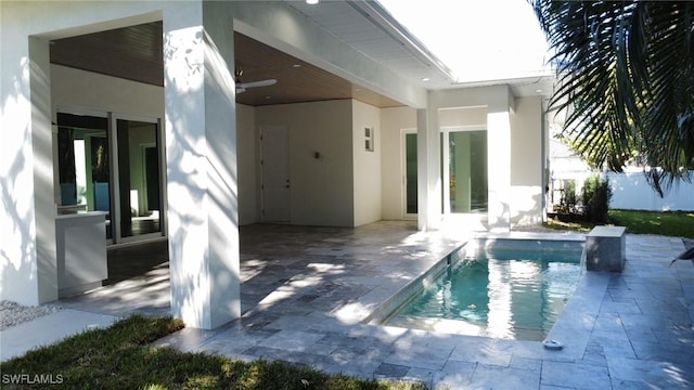 back of house featuring stucco siding, a fenced in pool, and a patio