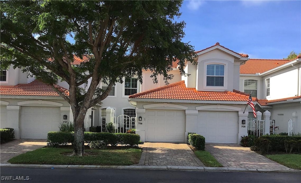 mediterranean / spanish-style house with a tiled roof, stucco siding, decorative driveway, and a garage
