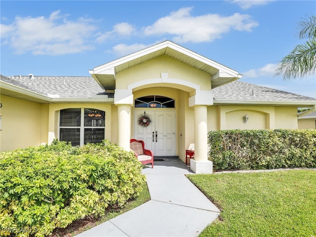 201 SE 4th St, Cape Coral, FL 33990 - doorway to property with a shingled roof, stucco siding, and a lawn