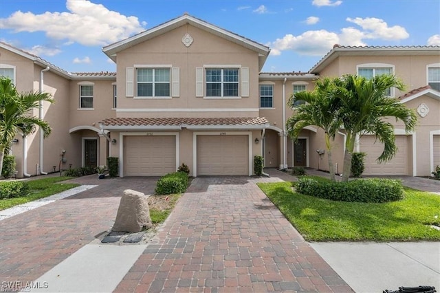 view of front of house featuring a tile roof, stucco siding, driveway, and an attached garage
