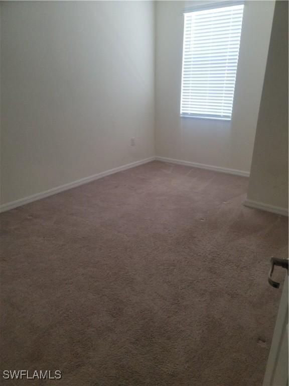 spare room featuring carpet flooring and baseboards