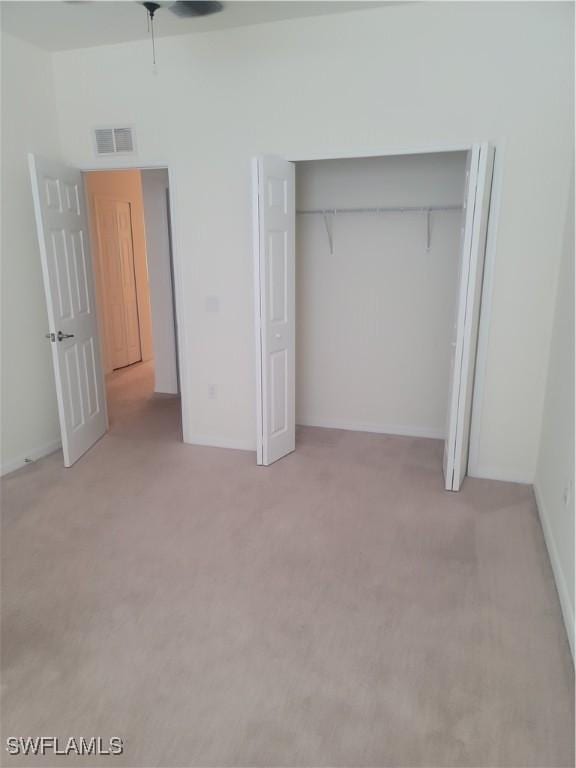 unfurnished bedroom featuring light carpet, a closet, and visible vents