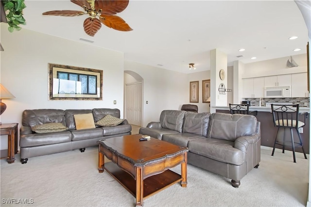 living room with arched walkways, light carpet, a ceiling fan, and recessed lighting