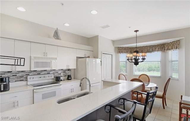 kitchen featuring white appliances, a sink, a breakfast bar area, backsplash, and white cabinetry