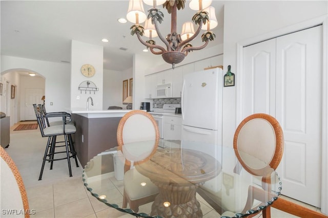 dining space with arched walkways, a chandelier, recessed lighting, and light tile patterned floors