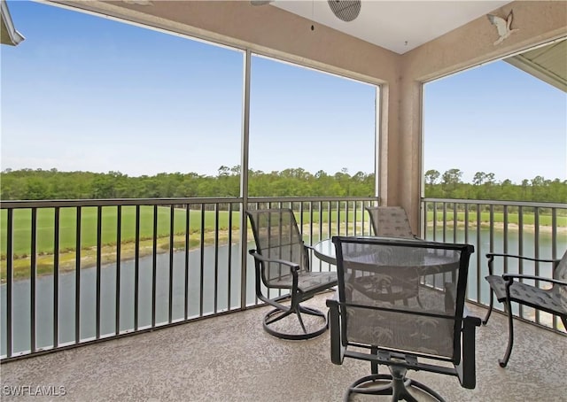 sunroom with a water view and view of scattered trees