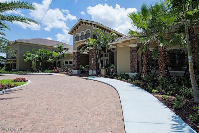 3599 Beaufort Ct, Naples, FL 34119 - view of front of property with curved driveway, stucco siding, a tiled roof, and stone siding