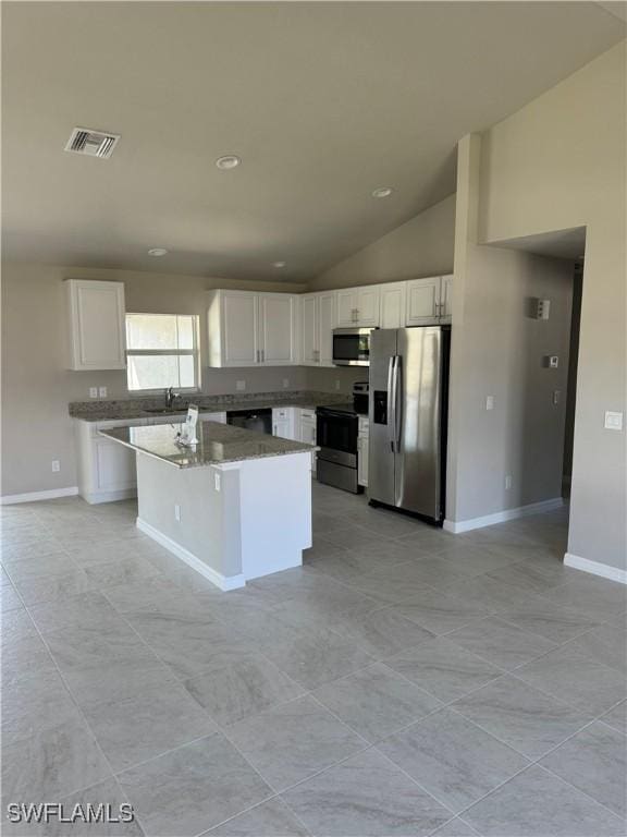 4334 SW 9th Pl, Cape Coral, FL 33914 - kitchen with stainless steel appliances, visible vents, vaulted ceiling, white cabinetry, and a center island