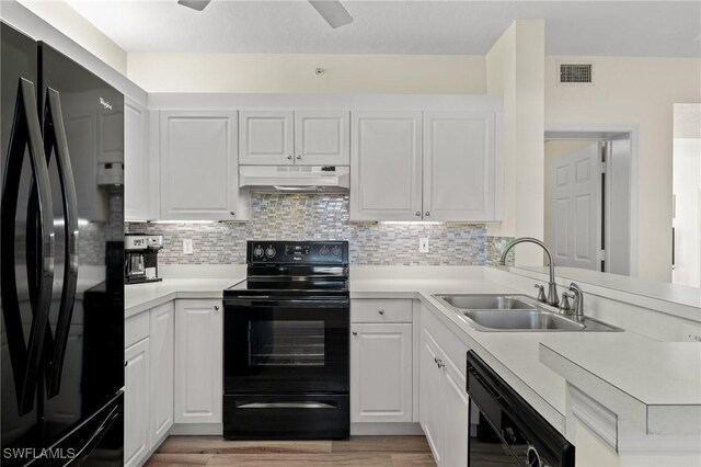 kitchen with black appliances, a sink, under cabinet range hood, white cabinetry, and light countertops
