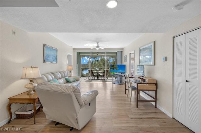 22748 Island Pines Way Unit 102, Fort Myers Beach, FL 33931 - living area with a ceiling fan, light wood-style flooring, baseboards, and a textured ceiling
