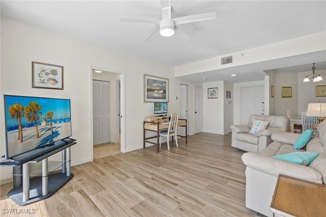 living area featuring ceiling fan, light wood finished floors, a chandelier, and baseboards