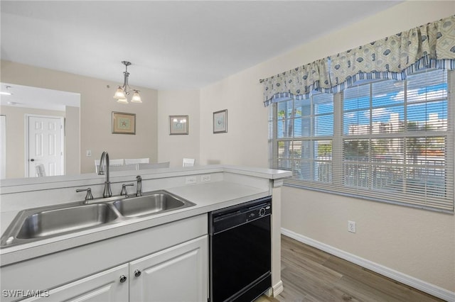 kitchen with black dishwasher, a sink, baseboards, wood finished floors, and hanging light fixtures