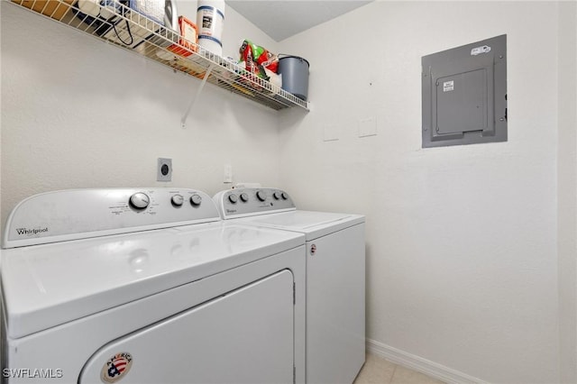 clothes washing area with electric panel, washing machine and clothes dryer, and baseboards