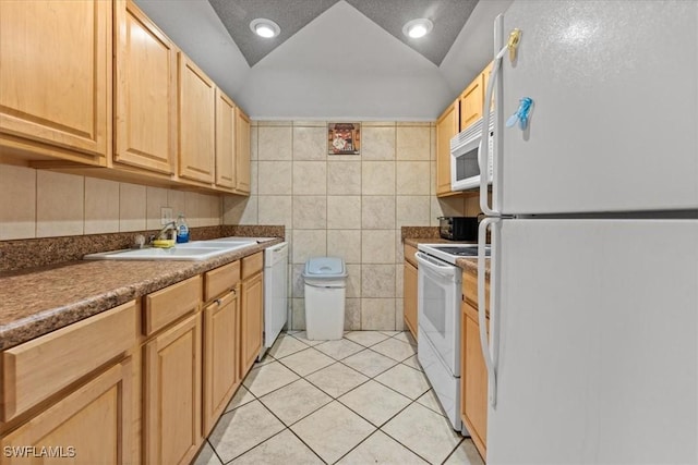 kitchen featuring white appliances, a sink, light tile patterned floors, tile walls, and light brown cabinetry