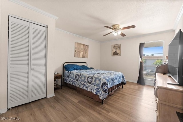 bedroom featuring wood finished floors, ornamental molding, baseboards, a closet, and ceiling fan