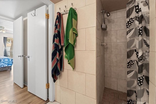 full bath featuring tiled shower, wood finished floors, and connected bathroom