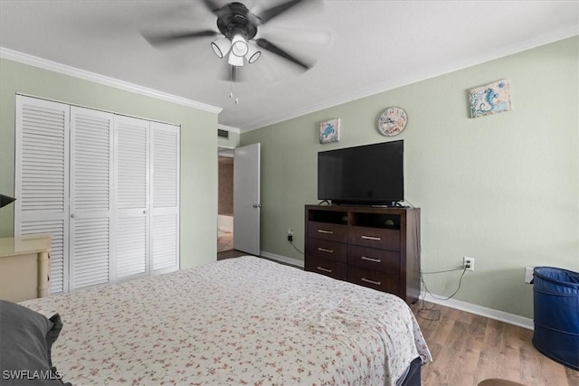 bedroom with a closet, crown molding, baseboards, wood finished floors, and ceiling fan