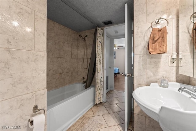 bathroom with tile walls, shower / tub combo with curtain, a sink, a textured ceiling, and tile patterned flooring