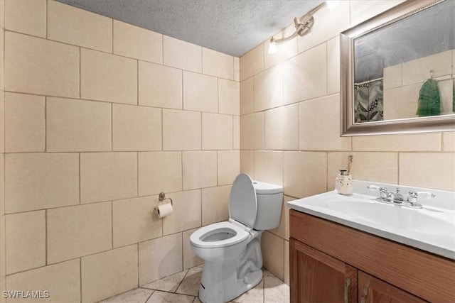 bathroom featuring toilet, tile walls, vanity, a textured ceiling, and tile patterned flooring