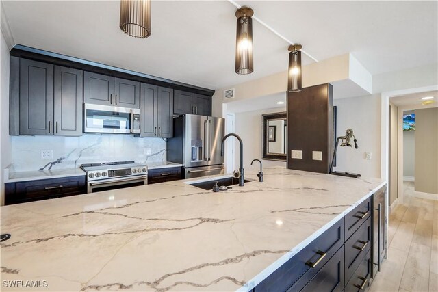 17080 Harbour Point Dr Unit 12B, Fort Myers, FL 33908 - kitchen featuring stainless steel appliances, a sink, light stone countertops, decorative backsplash, and decorative light fixtures