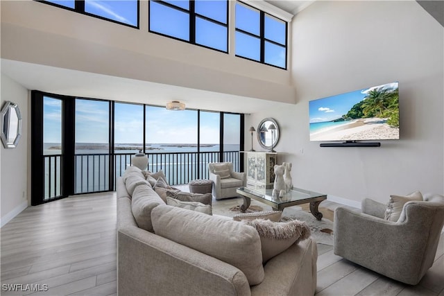 17080 Harbour Point Dr Unit 12B, Fort Myers, FL 33908 - living room with baseboards, light wood-style flooring, and a towering ceiling
