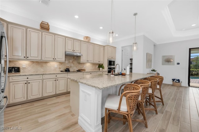 28009 Foxrock Ct, Bonita Springs, FL 34135 - kitchen with light wood finished floors, cream cabinetry, appliances with stainless steel finishes, and under cabinet range hood