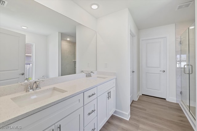 bathroom featuring double vanity, visible vents, a shower stall, and a sink