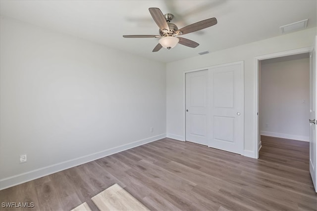 unfurnished bedroom featuring baseboards, a closet, visible vents, and wood finished floors