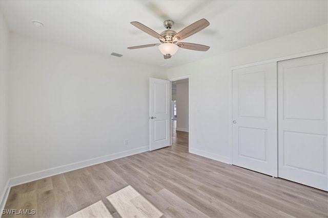 unfurnished bedroom with a closet, visible vents, ceiling fan, light wood-style flooring, and baseboards