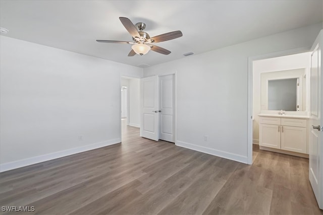 unfurnished bedroom with wood finished floors, ensuite bath, visible vents, ceiling fan, and baseboards