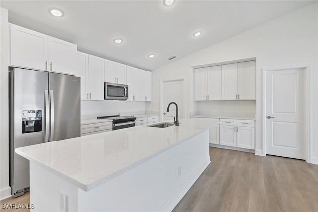 kitchen with a sink, stainless steel appliances, white cabinets, a center island with sink, and lofted ceiling