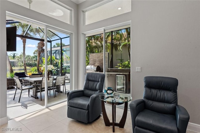 living area featuring healthy amount of natural light, light tile patterned floors, and baseboards