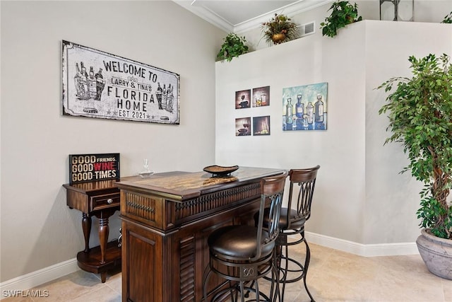 bar area featuring ornamental molding, baseboards, and light tile patterned flooring